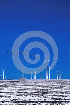 Different windmills with power pole transmission line in winter landscape