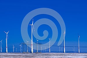 Different windmills with transmission line in winter landscape