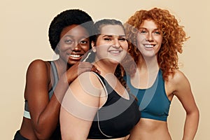 Different Women. Group Of Diversity Models Portrait. Smiling International Female In Fitness Clothes Posing On Beige Background.