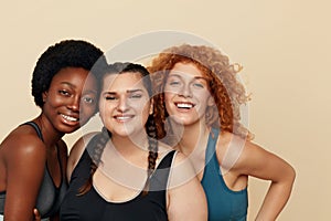 Different Women. Group Of Diversity Models Portrait. Smiling Multiethnic Female In Fitness Clothes Posing On Beige Background.