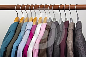 Different women`s office classic jackets and shirts hang on a hanger for storing clothes. The choice of style of fashionable