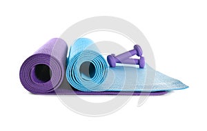 Different yoga mats with dumbbells on white background