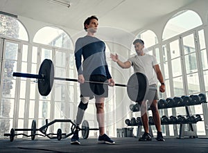 differently abled athlete weightlifting with his coach in the gym. Man with prosthetic leg being coached by his trainer photo