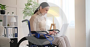 Differently abled woman sitting in wheelchair working on laptop