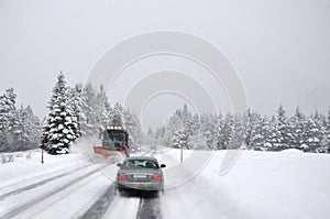 Difficult traffic after snowing. The snow cleaner operatively cleans the snow-covered mountain road