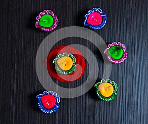 Diffrent colour of diyas arranged on black background