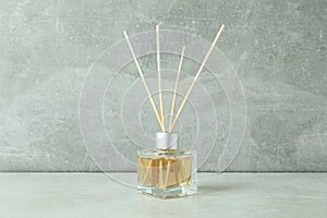 Diffuser bottle with sticks against gray textured background