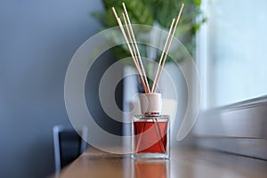 Diffuser with wooden sticks on the windowsill, close-up