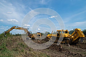 Digger and bulldozer clearing forest land.