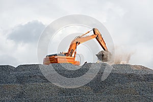 Digger collecting stone for road building