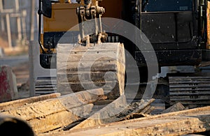 Digger parked at construction site with metal bar. Backhoe after work. Earth moving machine. Excavation vehicle. Construction site