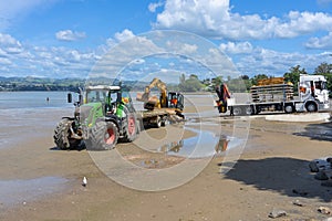 Digger on trailer behind tractor on beach