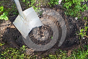 Digging a plant hole in the ground with a spade, brown sandy soil and some weeds around, gardening concept, copy space, copy space