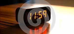 A digital alarm clock with a display and the time at 11:59, or one minute before noon or midnight. Design element or background