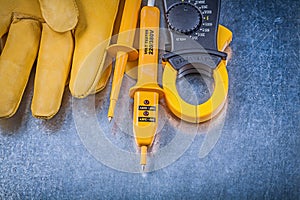 Digital amperemeter electrical tester safety gloves on metallic