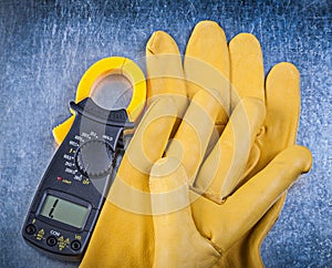 Digital amperemeter safety gloves on metallic background