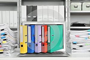 Digital archive. Laptop with folders sticking out of screen in office