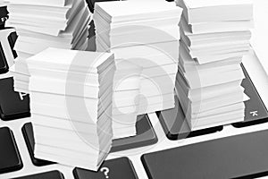 Digital archive. Laptop keyboard with downsized stacked papers, closeup photo