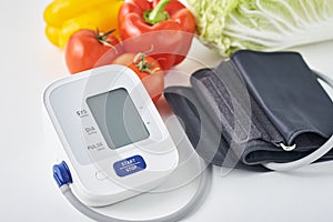 Digital blood pressure monitor and fresh vegetables on the table. Healthcare concept