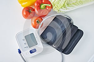 Digital blood pressure monitor and fresh vegetables on the table. Healthcare concept