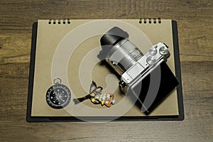 Digital Camera on Brown paper with compass and fish necklace