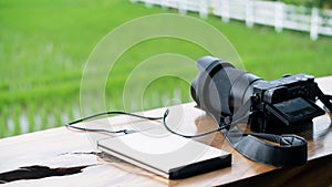 A digital camera charging a power bank that sits on the table and looks out into the field.