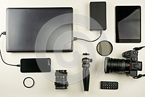 Digital camera with lenses and equipment of the professional photographer on white leather background