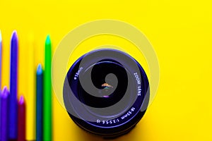 Digital camera zoom lens placed on yellow background.