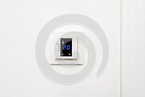 Digital climate control on white wall.