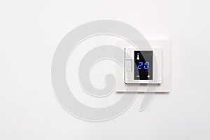 Digital climate control on white wall.