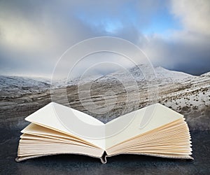 Digital composite of Beautiful landscape of snow covered mountains during late afternoon in Winter in pages of open book