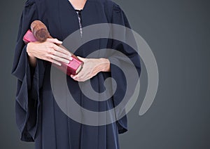 Female judge mid section with book and gavel against grey background