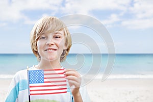 Happy boy holding a USA flag in the beach