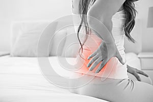 Digital composite of highlighted spine of woman with back pain