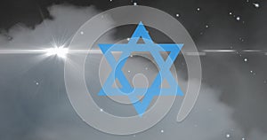 Digital composite image of blue star of david against cloud in sky at night