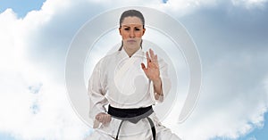 Digital composite image of caucasian female marital artist with black belt against blue sky
