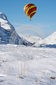 Digital composite image of hot air balloons flying over Beautiful iconic landscape Winter image of Stob Dearg Buachaille Etive Mor