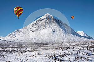 Digital composite image of hot air balloons flying over Beautiful iconic landscape Winter image of Stob Dearg Buachaille Etive Mor