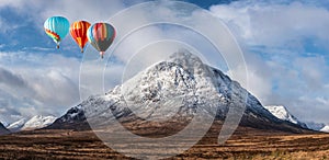 Digital composite image of hot air balloons flying over Beautiful iconic landscape Winter image of Stob Dearg Buachaille Etive Mor