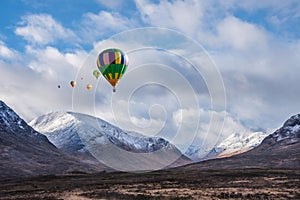 Digital composite image of hot air balloons flying over Majestic beautiful Winter landscape image of Lost Valley in Scotland