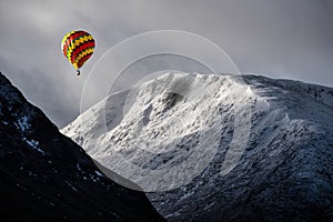 Digital composite image of hot air balloons flying over Majestic beautiful Winter landscape image of Lost Valley in Scotland