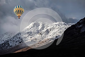 Digital composite image of hot air balloons flying over Majestic beautiful Winter landscape image of Lost Valley in Scotland with