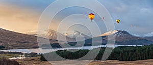 Digital composite image of hot air balloons flying over Majestic beautiful Winter sunrise panorama landscape image of glowing