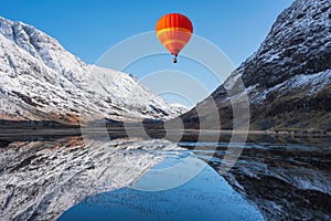 Digital composite image of hot air balloons flying over Stunning Winter landscape image of Loch Achtriochan in Scottish Highlands