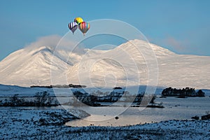 Digital composite image of hot air balloons flying over Stunning Winter landscape image looking across Lochan Na h-Achlaise