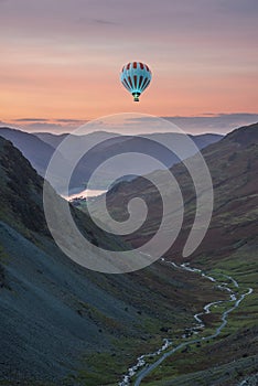 Digital composite image of hot air balloons over Stunning colorful landscape image of view down Honister Pass to Buttermere from