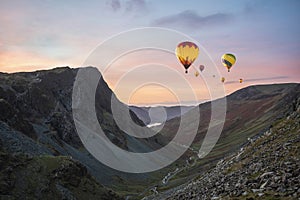 Digital composite image of hot air balloons over Stunning colorful landscape image of view down Honister Pass to Buttermere from