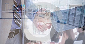 Digital composite image of mid section of two businessmen shaking hands against empty office