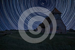 Digital composite image of star trails around Polaris with Ancient Medieval church landscape