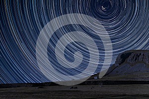 Digital composite image of star trails around Polaris with landscape of Norber Ridge in Yorkshire Dales National Park